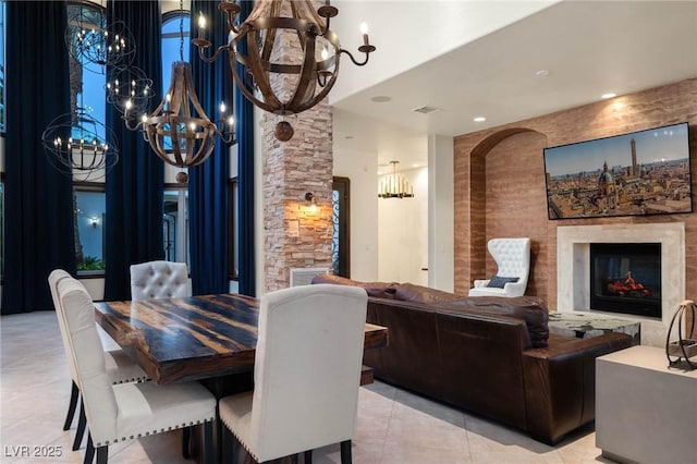 dining space with an inviting chandelier, a fireplace, visible vents, and light tile patterned flooring