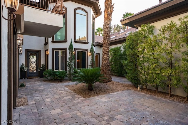 property entrance featuring a patio, a balcony, and stucco siding