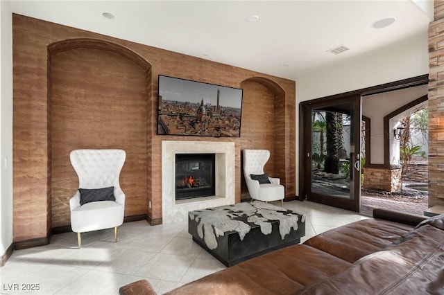 living area with light tile patterned floors, visible vents, and a glass covered fireplace