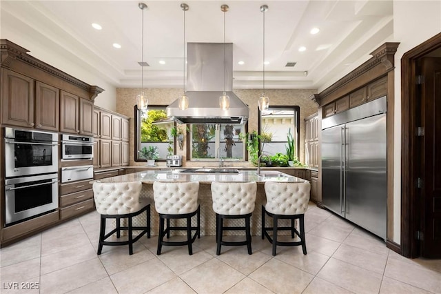 kitchen featuring a warming drawer, appliances with stainless steel finishes, island exhaust hood, and light stone countertops