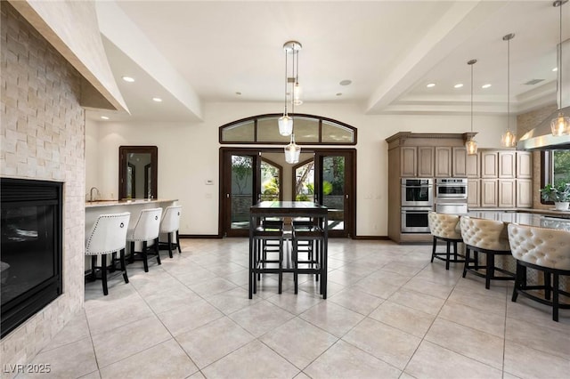 dining space with light tile patterned floors, baseboards, and a glass covered fireplace