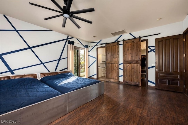 unfurnished bedroom featuring wood finished floors, visible vents, and a barn door