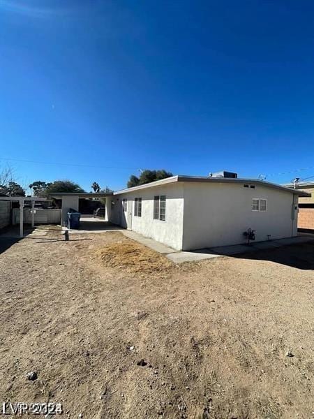 view of side of home with fence and stucco siding