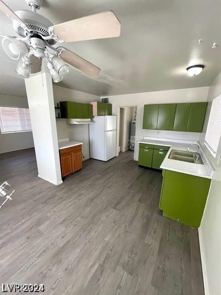 kitchen featuring dark wood-style flooring, a sink, light countertops, freestanding refrigerator, and green cabinetry