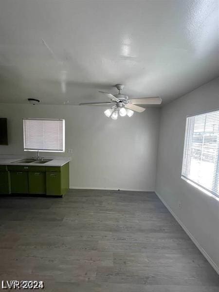 spare room featuring ceiling fan, wood finished floors, a sink, and baseboards