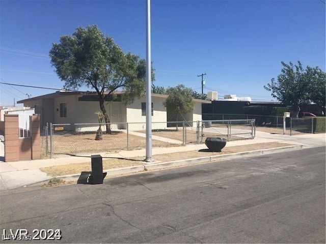 ranch-style house featuring a fenced front yard, concrete driveway, and stucco siding