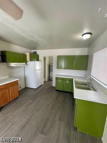 kitchen featuring a sink, light countertops, freestanding refrigerator, dark wood-style floors, and green cabinetry