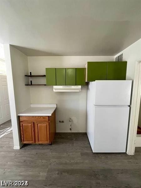 kitchen featuring dark wood-style floors, freestanding refrigerator, brown cabinets, and light countertops