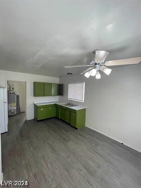 kitchen with dark wood-style flooring, light countertops, water heater, green cabinets, and a sink