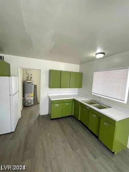 kitchen with gas water heater, freestanding refrigerator, light countertops, green cabinets, and a sink