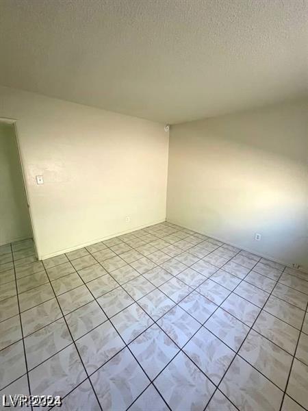 spare room with a textured ceiling and light tile patterned flooring