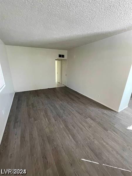 interior space featuring a textured ceiling, dark wood-type flooring, and visible vents