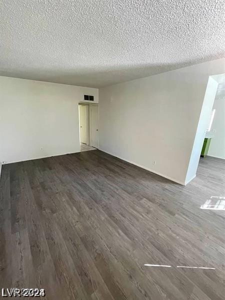 spare room featuring a textured ceiling, dark wood finished floors, and visible vents