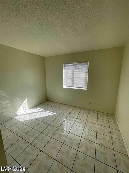 spare room with light tile patterned floors and a textured ceiling