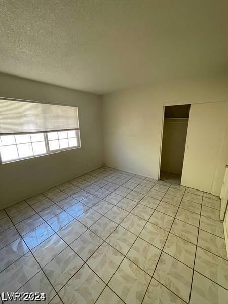 unfurnished room with a textured ceiling and light tile patterned floors