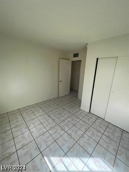 unfurnished bedroom featuring light tile patterned floors, visible vents, and a closet