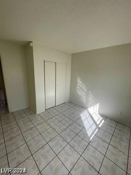 unfurnished bedroom with light tile patterned floors, a closet, and a textured ceiling