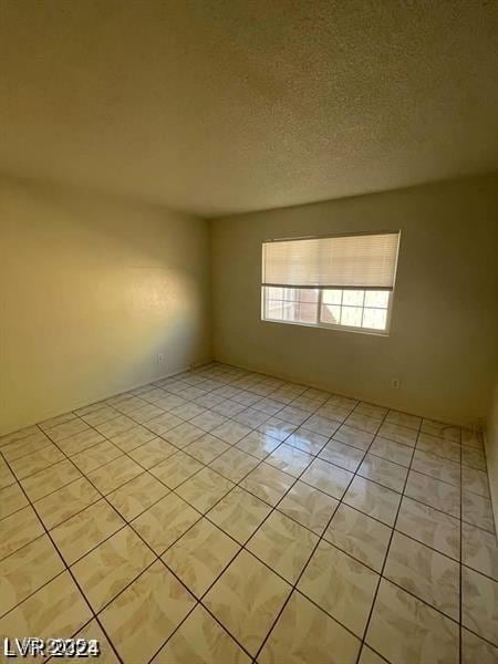 empty room with a textured ceiling and light tile patterned floors