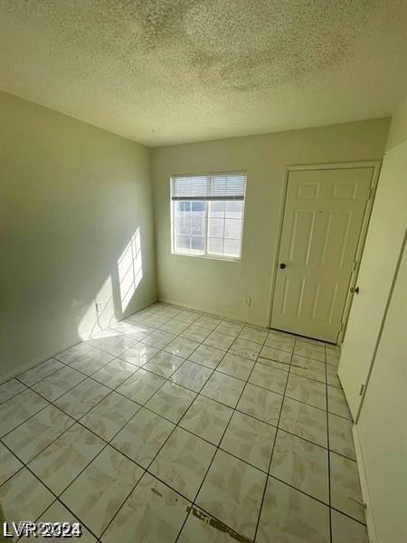 unfurnished room featuring light tile patterned floors and a textured ceiling