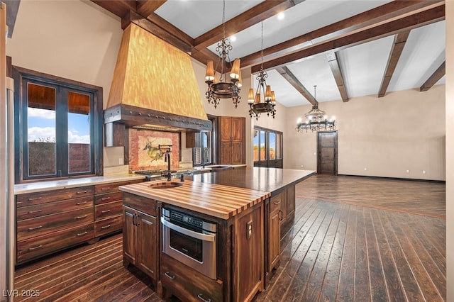 kitchen featuring butcher block countertops, dark wood-type flooring, oven, custom exhaust hood, and a chandelier