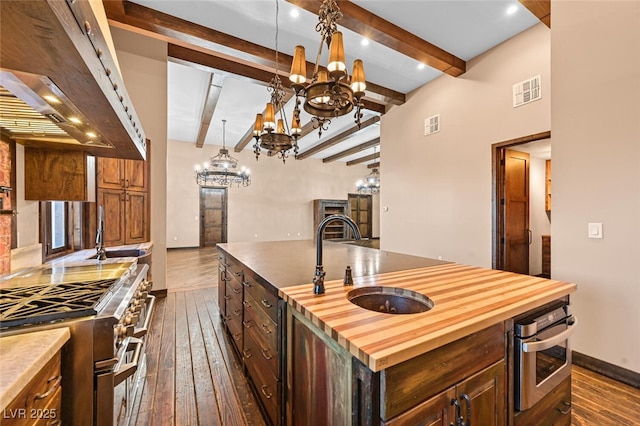 kitchen with dark wood-style floors, stainless steel appliances, butcher block counters, visible vents, and a sink