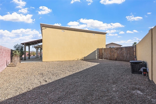 view of side of home featuring stucco siding, a fenced backyard, and a patio