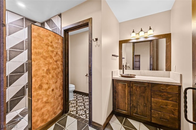 bathroom with toilet, tile patterned flooring, baseboards, and vanity