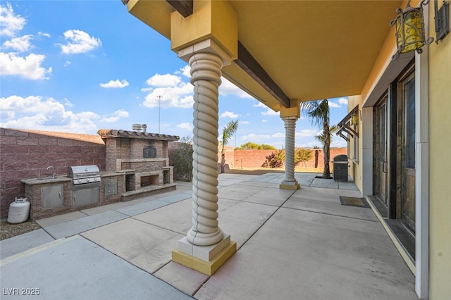 view of patio with exterior kitchen, an outdoor stone fireplace, area for grilling, and a fenced backyard