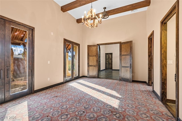 unfurnished room featuring an inviting chandelier, a high ceiling, baseboards, and beamed ceiling