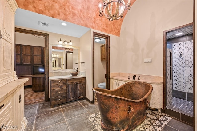 full bath with stone tile floors, visible vents, vaulted ceiling, a tile shower, and vanity