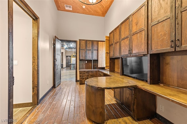 bar featuring visible vents, hardwood / wood-style floors, built in study area, wooden ceiling, and baseboards