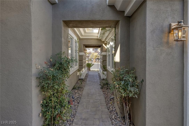 view of side of home featuring a gate and stucco siding