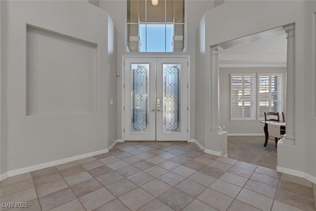 entrance foyer featuring light tile patterned floors, baseboards, french doors, ornate columns, and crown molding