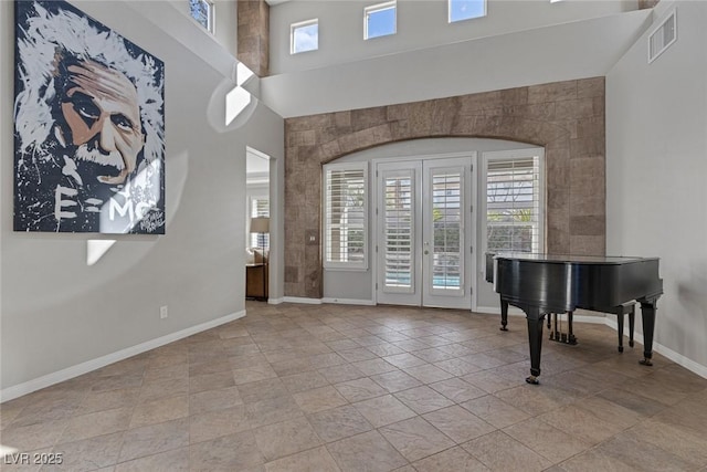 entryway with french doors, visible vents, a towering ceiling, and baseboards