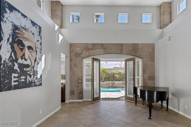 foyer entrance with a towering ceiling, visible vents, and baseboards