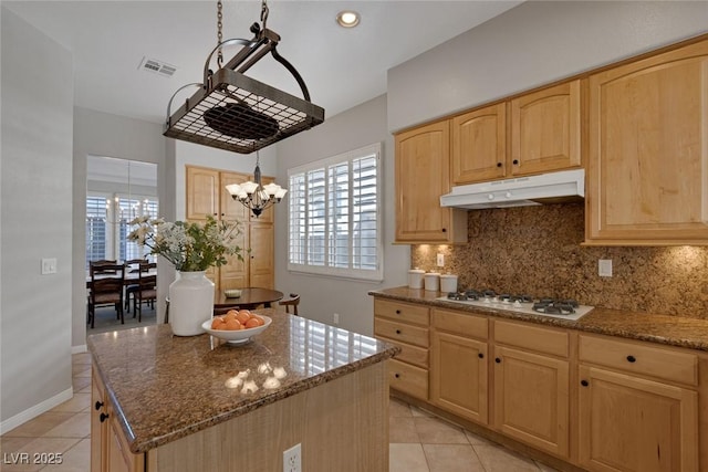 kitchen with stone counters, a center island, white gas stovetop, visible vents, and under cabinet range hood