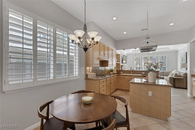 kitchen with a sink, a healthy amount of sunlight, open floor plan, light brown cabinetry, and pendant lighting