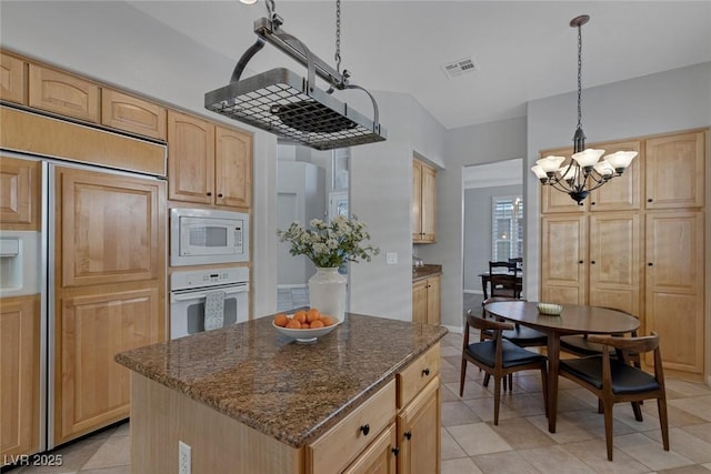 kitchen with built in appliances, visible vents, hanging light fixtures, a center island, and dark stone countertops