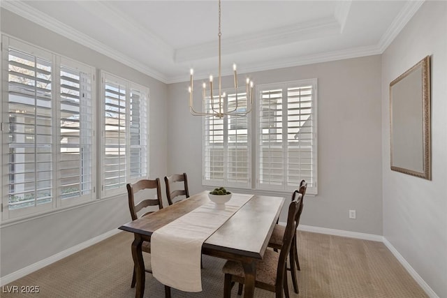 carpeted dining space with a chandelier, a tray ceiling, ornamental molding, and baseboards