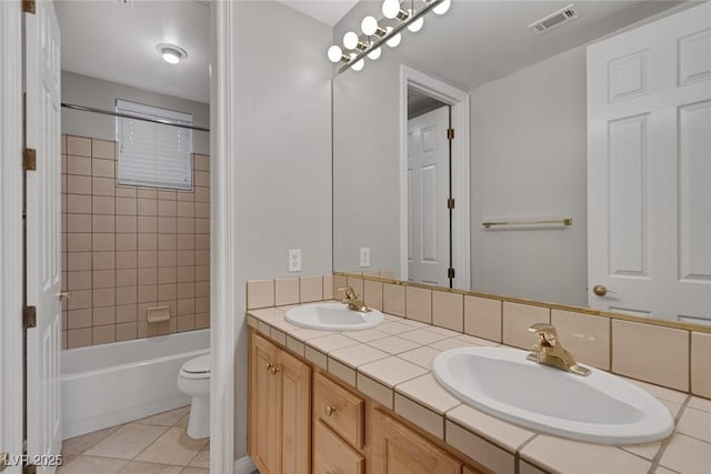 bathroom featuring toilet, shower / tub combination, visible vents, and a sink