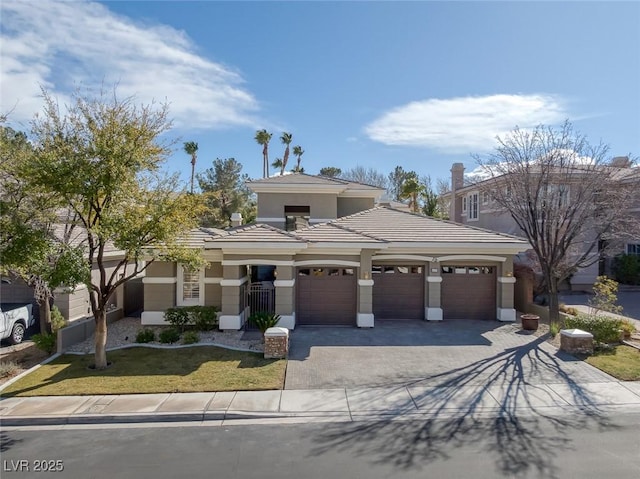 view of front of home featuring decorative driveway, an attached garage, a tile roof, and stucco siding