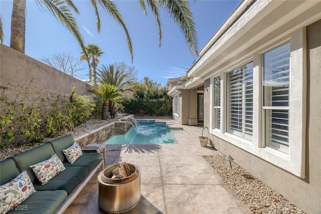 pool with a fenced backyard, a patio, and an outdoor living space with a fire pit