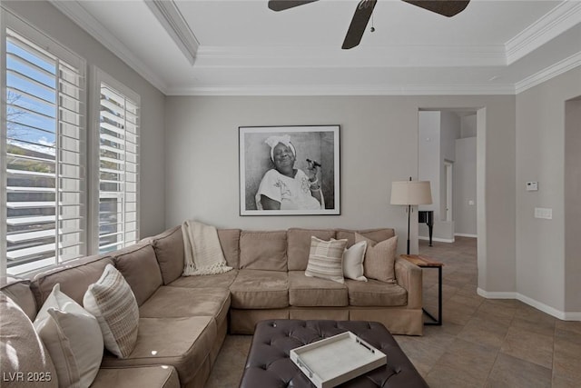 living room featuring ceiling fan, light tile patterned flooring, baseboards, a tray ceiling, and crown molding