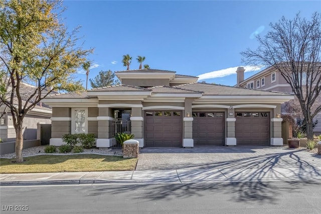 prairie-style home with a garage, driveway, a tiled roof, and stucco siding