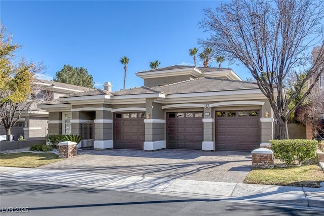 prairie-style home with a garage, decorative driveway, and stucco siding