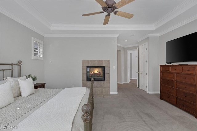 bedroom with light carpet, baseboards, a tile fireplace, ornamental molding, and a tray ceiling