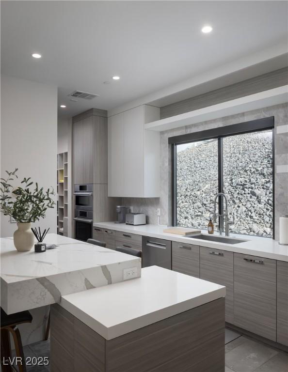 kitchen featuring tasteful backsplash, modern cabinets, stainless steel appliances, light countertops, and a sink