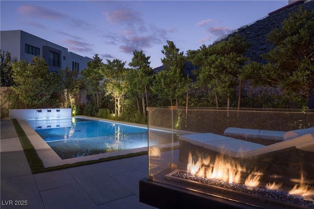 pool at dusk with a fenced in pool and an outdoor fire pit