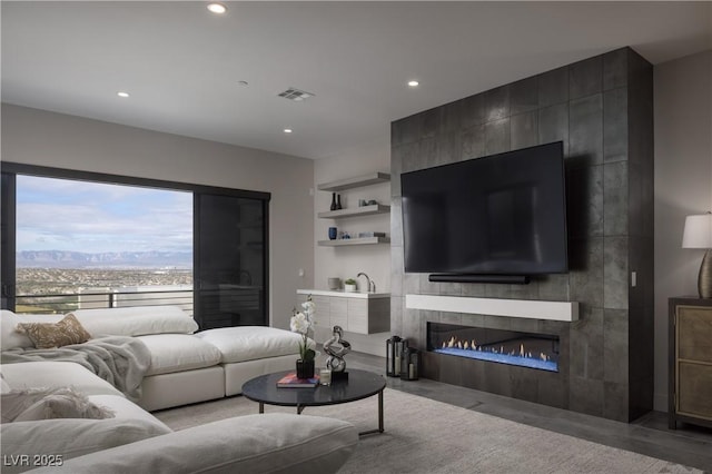 living room featuring recessed lighting, a large fireplace, and visible vents