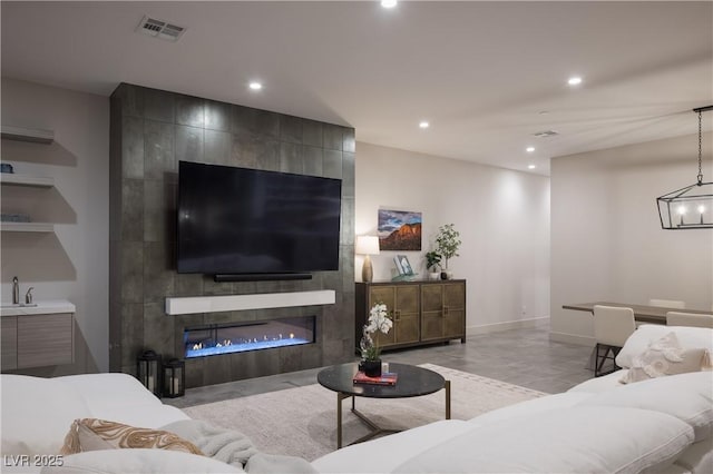 living room featuring baseboards, a tiled fireplace, visible vents, and recessed lighting